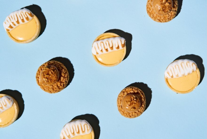 A pale blue backdrop with small tarts and biscuits. 