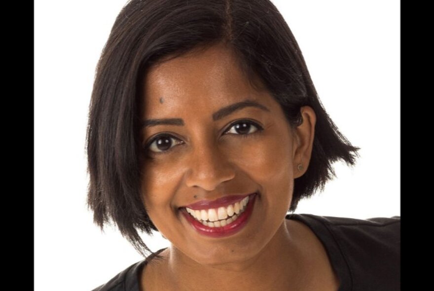 Author Sashi Perera, smiling at the camera in front of a stark white background.