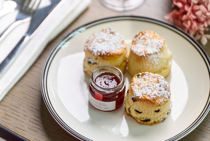 Scones and jam on a plate, as part of a high tea.