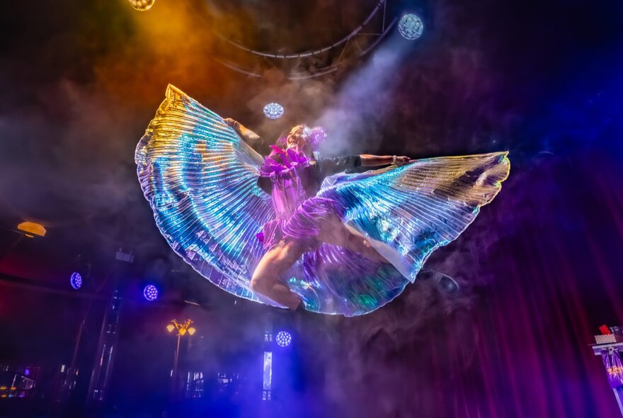 A children's circus performer leaping in the air with gauze fabric outstretched behind her like wings.