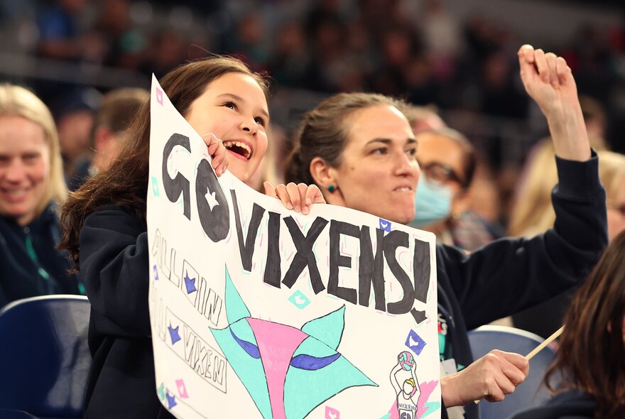 Netball fans holding posters in the stands.