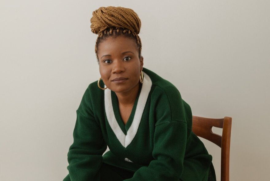 Santilla Chingaipe, her hair roped on top of her head, leaning forward wearing hoop earrings.