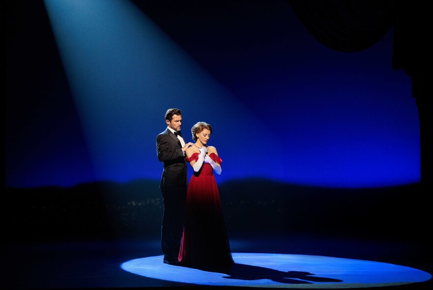 Two actors wearing formal clothes in a spotlight on a theatre stage during a performance of Pretty Woman: The Musical.
