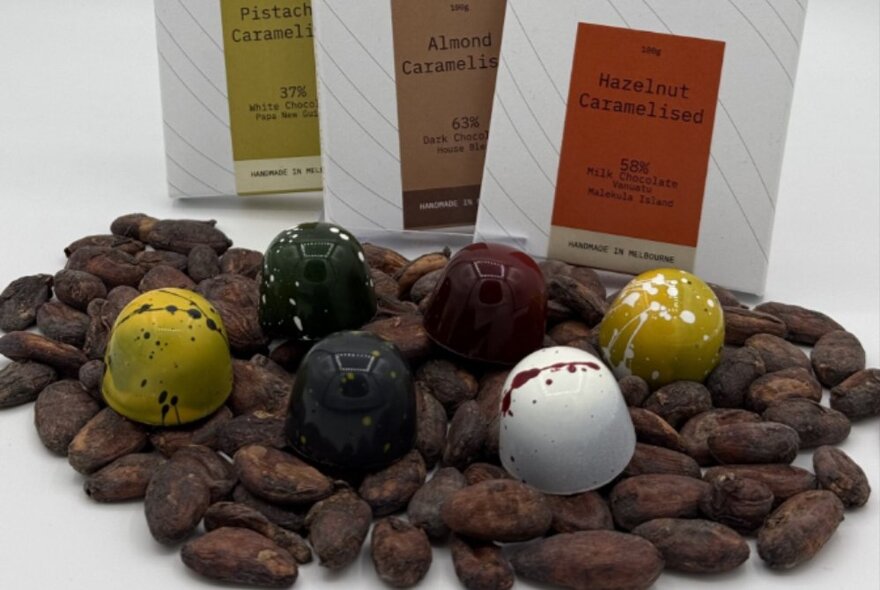 A selection of decadent chocolates presented on a layer of dates, with three white cardboard packets behind.