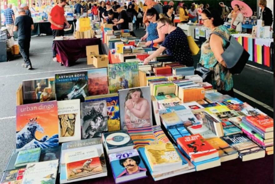 Long line of tables covered in books.