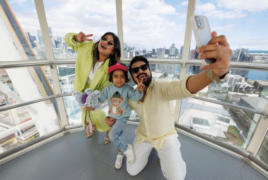 A family on Melbourne Star Observation Wheel taking a selfie high above the ground. 