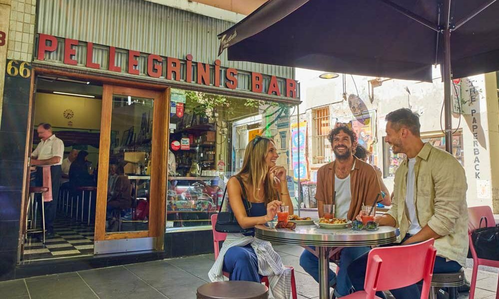 Three friends sitting at a table outside a corner cafe