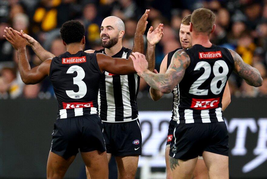 Collingwood players celebrating during a match. 