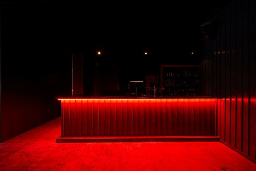 Dark room showing red carpet and an under-lit bench or counter top.