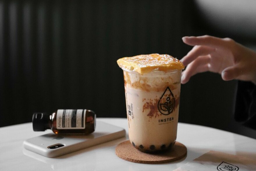 Hand adjusting a dessert in a tall container.