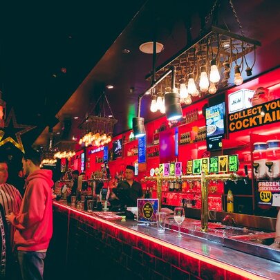Colourful bar with posters on the wall behind the taps.