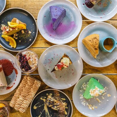 Bird's-eye view of multiple plates of desserts on a wooden surface.