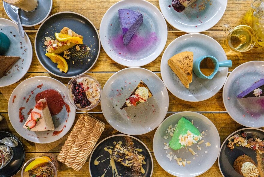 Bird's-eye view of multiple plates of desserts on a wooden surface.