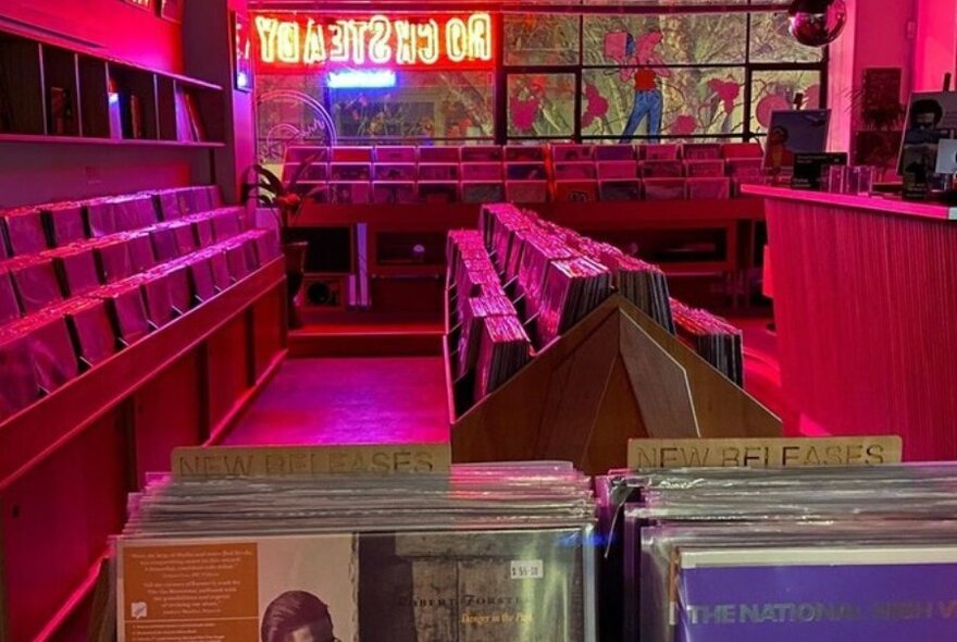 A record store lit up by a red and blue neon sign