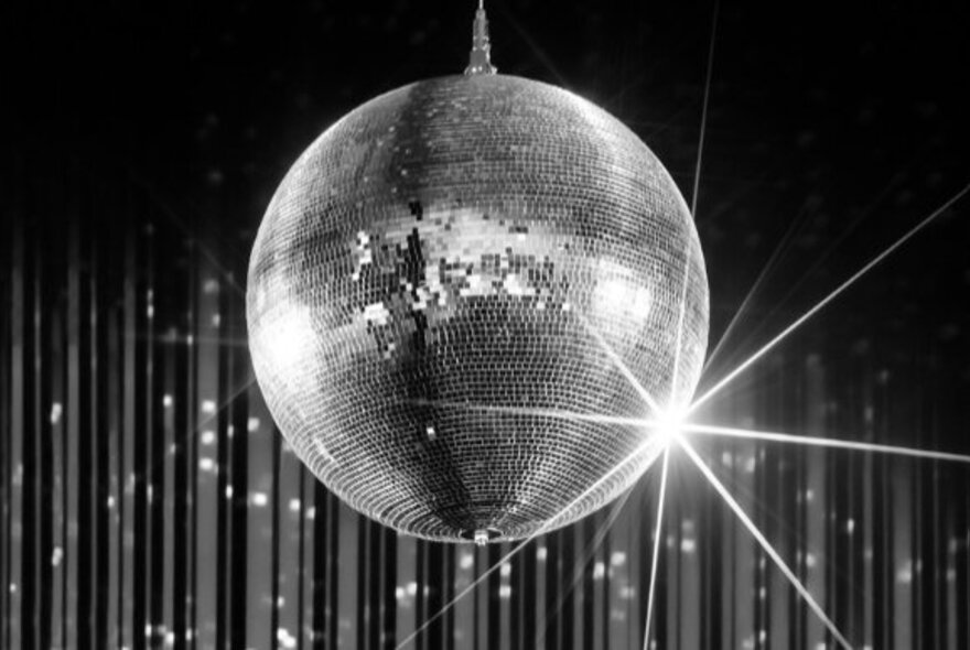 Silver glitter ball in front of shiny streamers.
