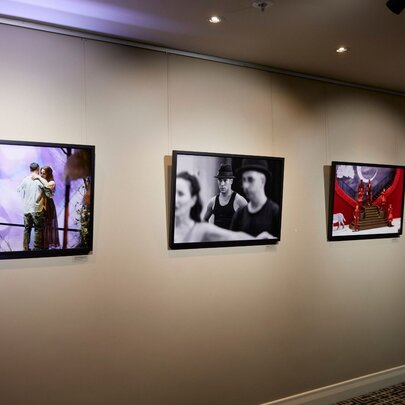 Printed and framed photographs of Opera performers hanging on a gallery wall.