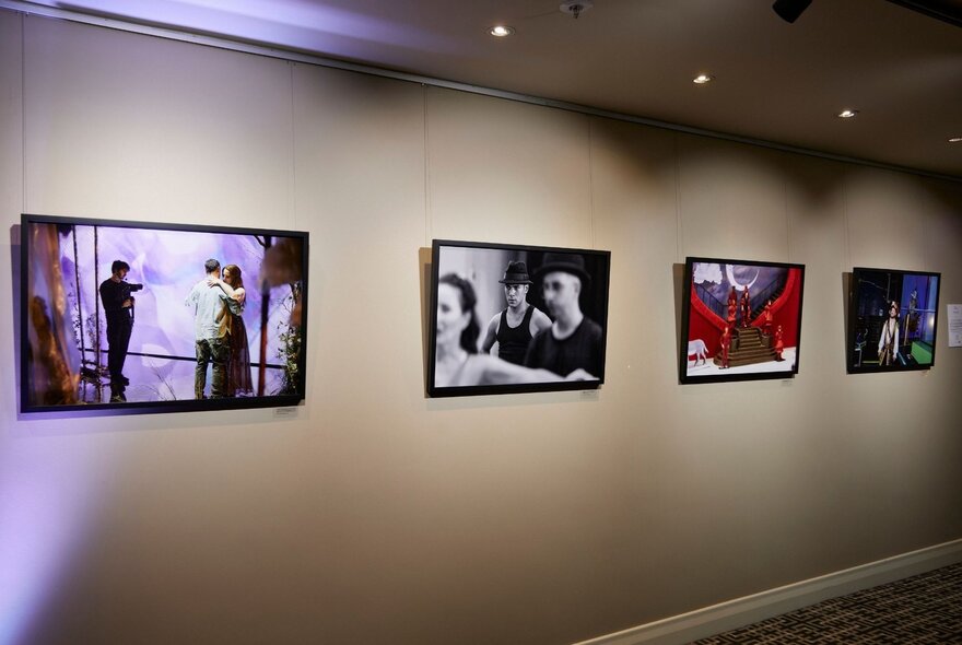 Printed and framed photographs of Opera performers hanging on a gallery wall.