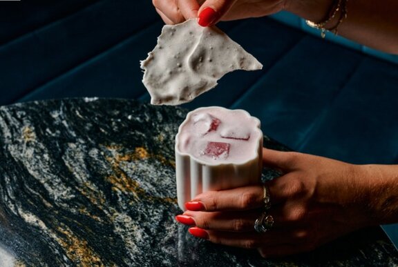 A hand dipping an oyster into a drink.
