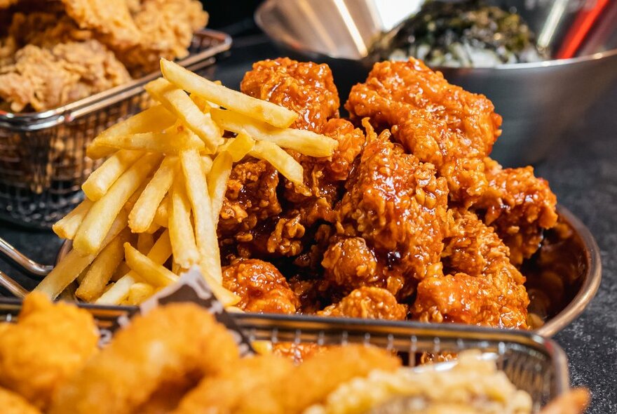 Metal baskets with fried chicken, chips and skides.