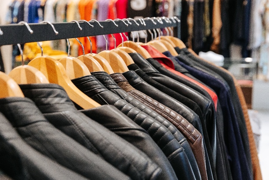 A row of black leather jackets, hanging on a clothing rail.