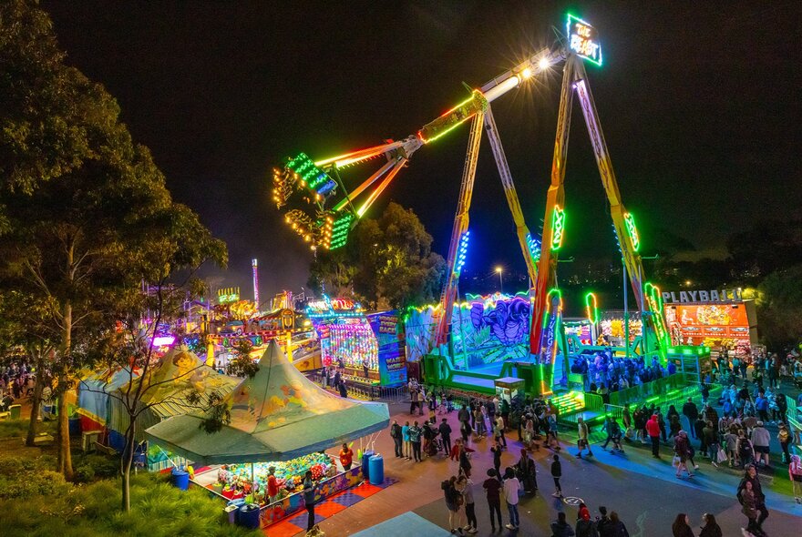 A giant swinging ride with neon lights at a carnival at night.