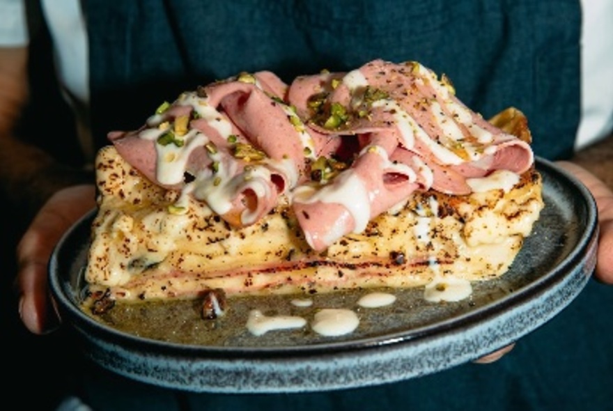Mortadella slices on top of a piece of lasagne on a plate