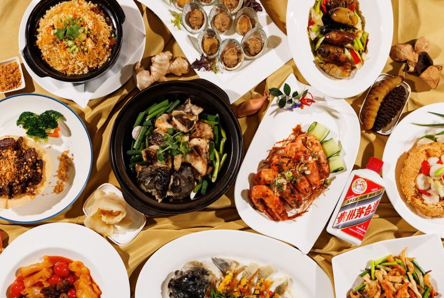 Many dishes of Chinese food on a table including rice and dumplings.