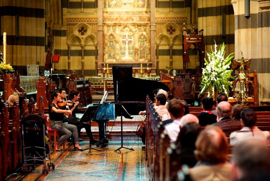 Musicians playing in St Paul's Cathedral to an audience sitting in pews. 