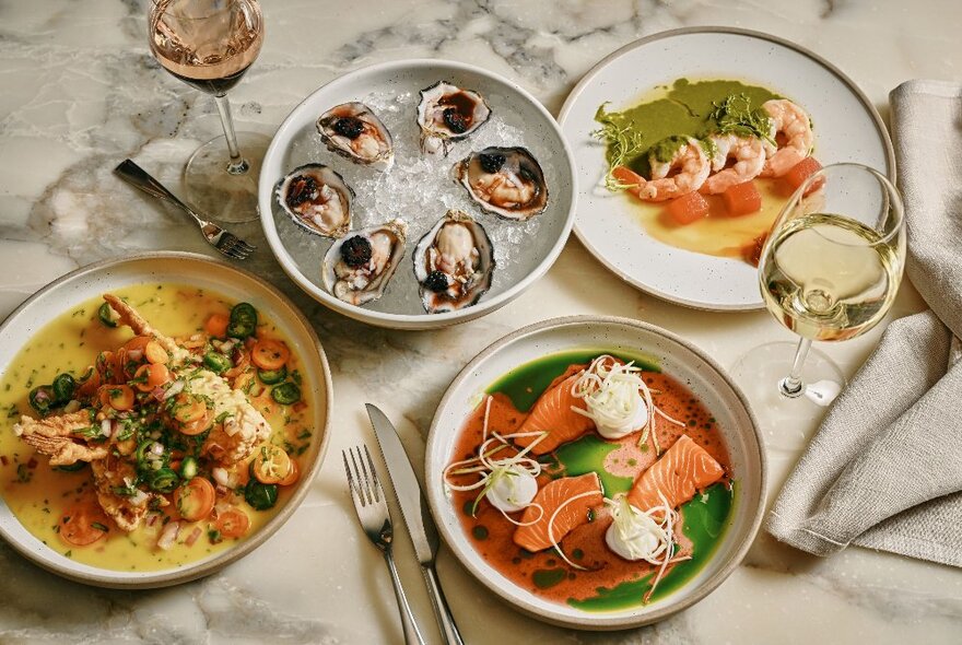 Looking down at a table with four different seafood dishes.