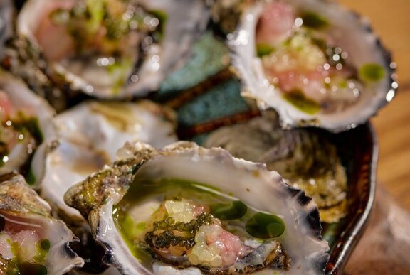 Freshly shucked oysters served with a garnish.