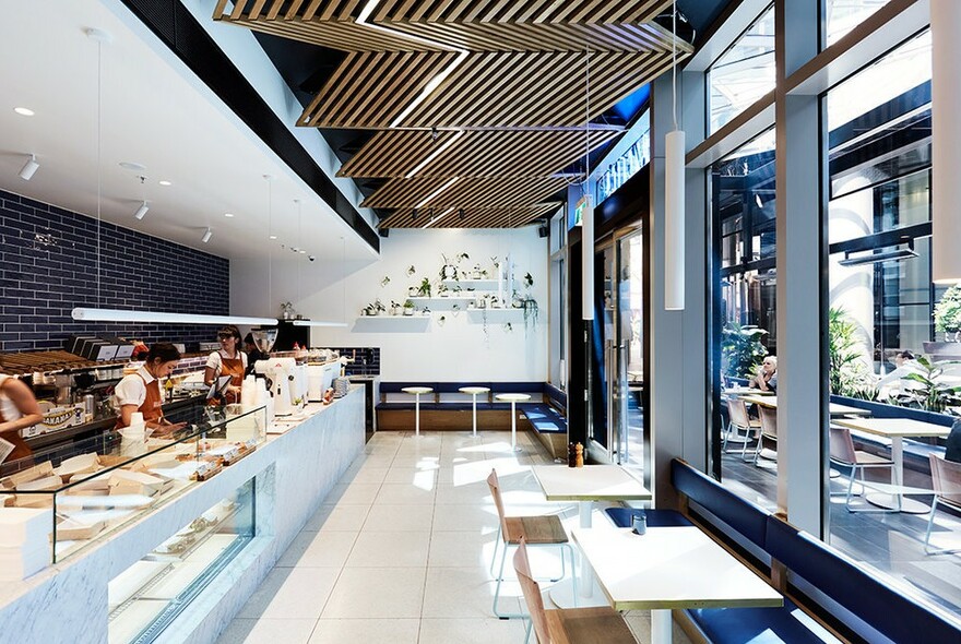 Inside Rustica's cafe at Rialto Towers, showing long display cabinet and small tables. 