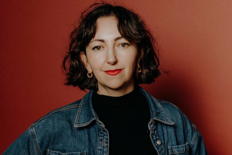 The academic Hannah McCann, with short dark bob length haircut, wearing a denim jacket, looking directly at the viewer.
