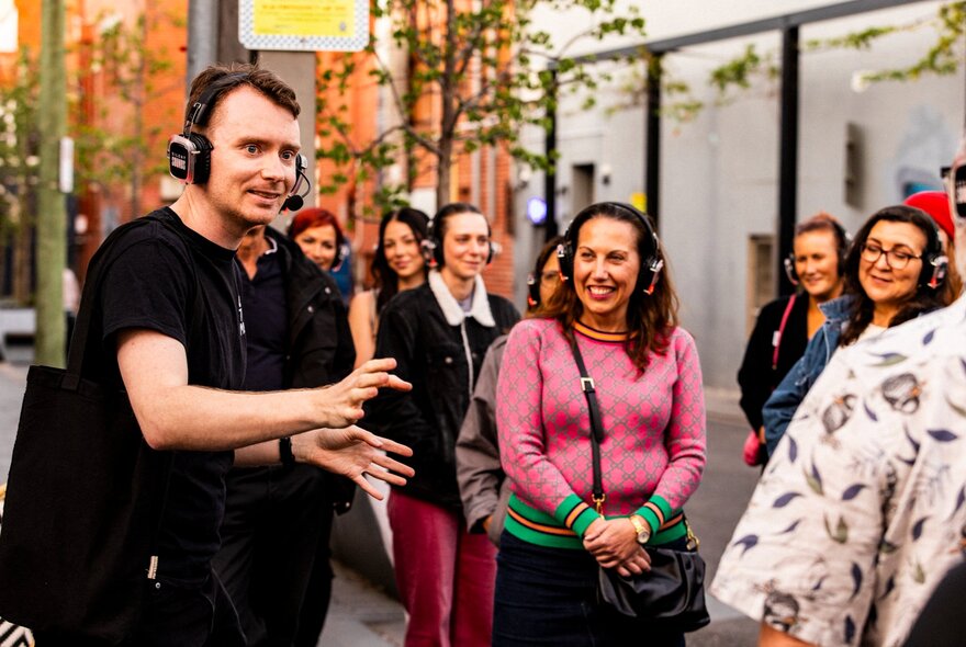 Comedian Matt Bell speaking to a group of people in an outdoor setting.