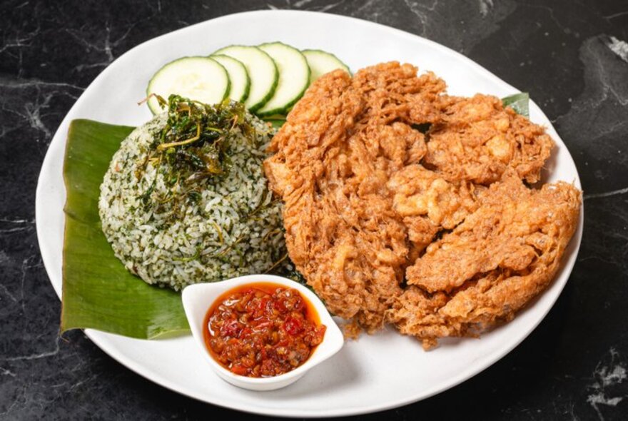 Fried puffs on a plate with a bowl of chilli sauce.
