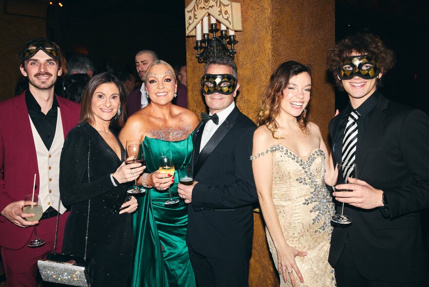 Diners wearing gowns and masks at a formal dinner.