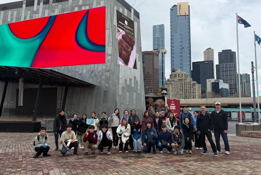 Group of people in Fed Square with city buildings in the background.