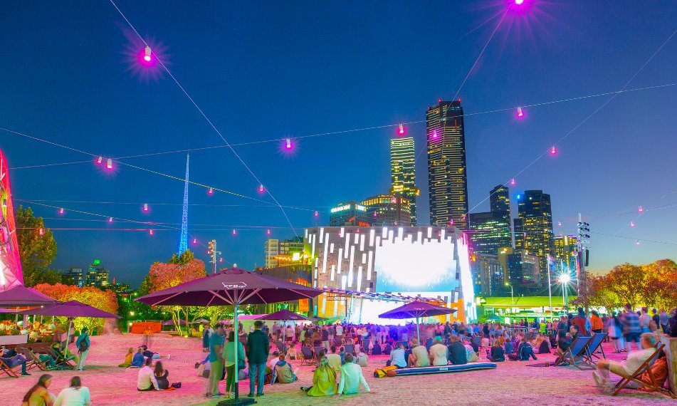 a crowd of people are watching a movie in a city square