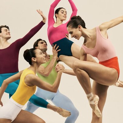 Five ballet dancers in a group pose, all in different positions and dressed in vibrant, contrasting dancewear.