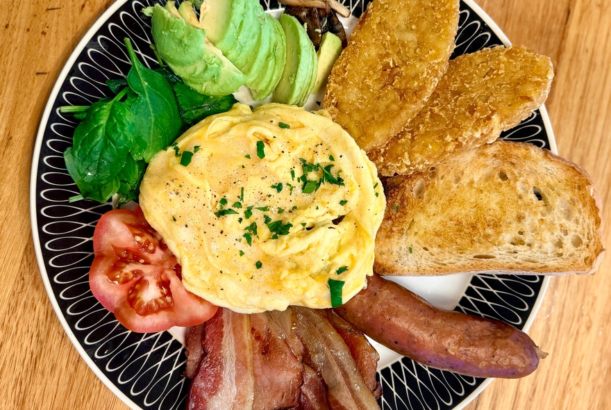 Aussie breakfast dish of scrambled eggs with bacon, avocado and toast.