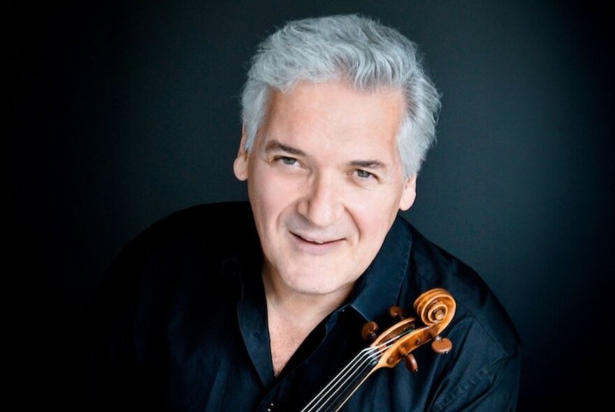 Grey-haired musician holding a violin.
