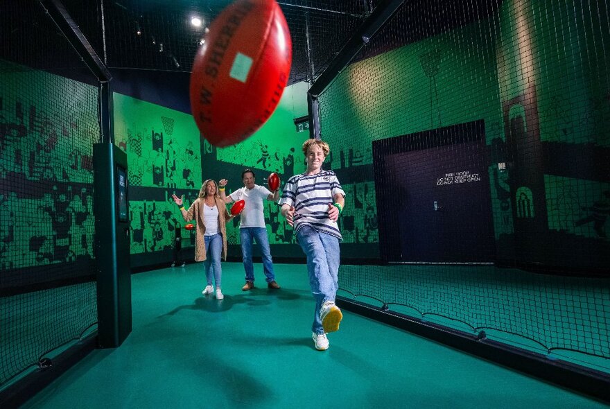 People playing with a football in a museum play space.