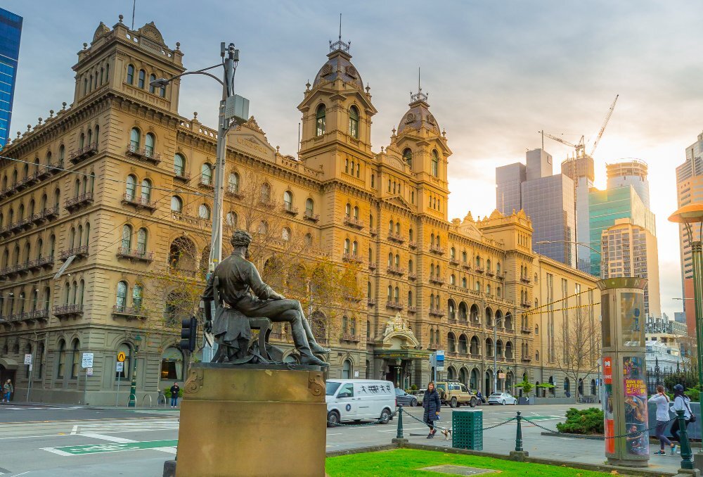 A grand hotel with a statue in the foreground.