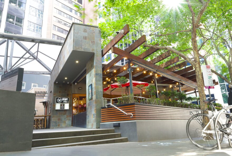 Exterior of Henry and The Fox, a restaurant and cafe in Melbourne, showing an outdoor deck area, steps up from the footpath and a tree.