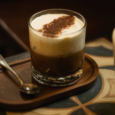 A glass of Vietnamese egg coffee featuring a thick, whipped egg yolk and condensed milk topping over dark coffee.