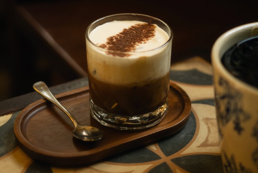 A glass of Vietnamese egg coffee featuring a thick, whipped egg yolk and condensed milk topping over dark coffee.