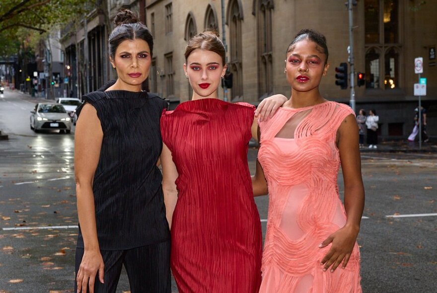 Models wearing summer sleeveless dresses, standing on a wet city street.