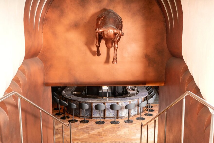 Stairs leading down stairs into a basement restaurant, with a metal animal displayed above the steps.