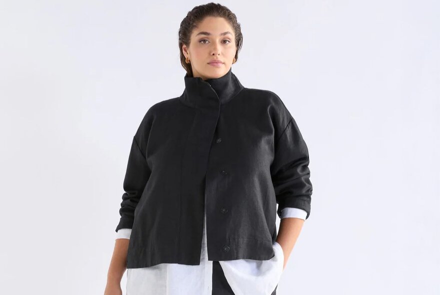 A model wearing a black cropped funnel neck jacket.
