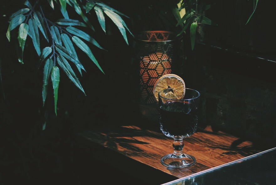 Cocktail on a table in a dimly-lit corner of a bar.