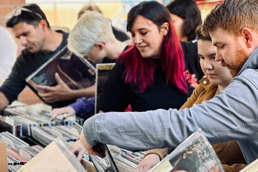 People looking through crates of vinyl records at a record fair market stall.